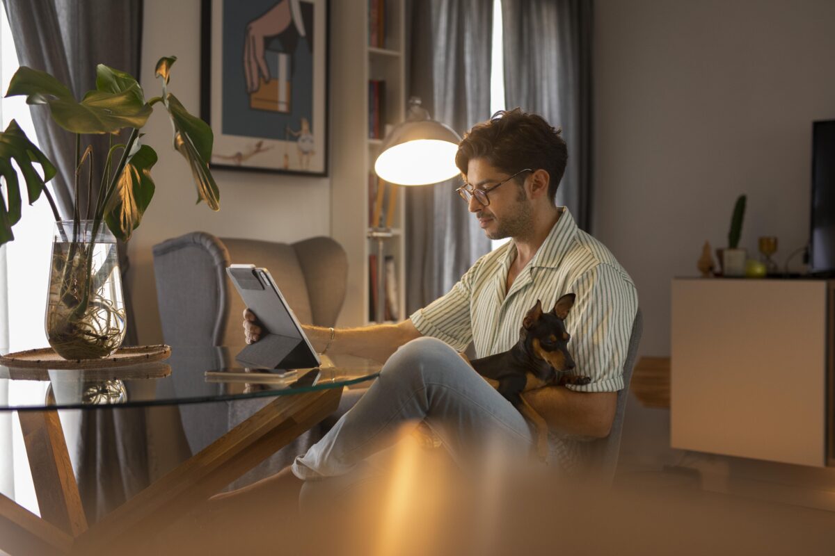 homem trabalhando com seu cachorro no colo, em regime home office