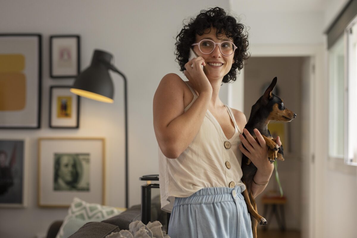 mulher em uma ligação de trabalho, com seu cachorro no colo, trabalhando em home office.