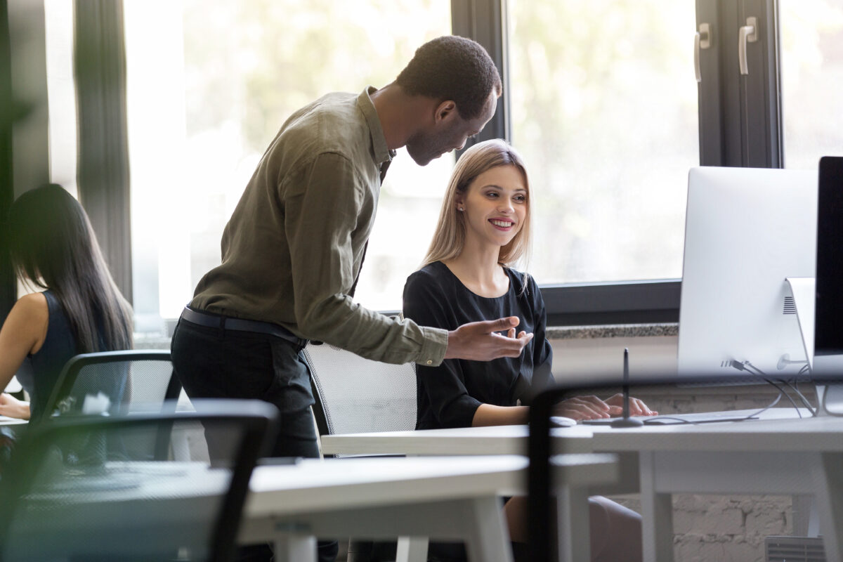 mulher jovem conversando com o colega no trabalho presencial