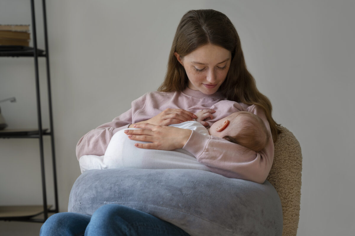 Mãe amamentando sua bebê em casa com auxílio-maternidade
